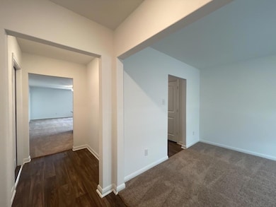 Hall with dark colored carpet, baseboards, and da