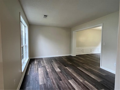 Unfurnished room featuring dark wood finished floors and a textured ceiling