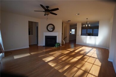Unfurnished living room with a chandelier, a fireplace with flush hearth, wood finished floors, and ceiling fan