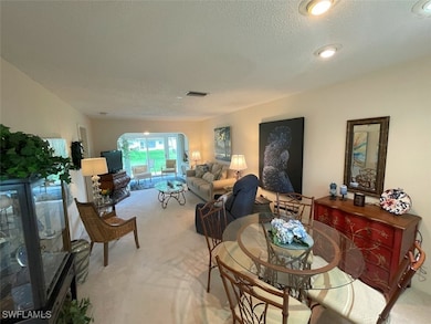 Living area with carpet, a textured ceiling, and a