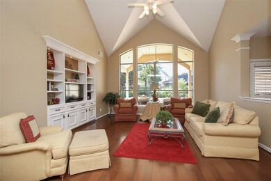This family room features a soaring ceiling, a wonderful panoramic window overlooking the back covered patio and pool area and a custom built-in entertainment center with extra storage cabinets.  Warm hardwoods add to the ambience!