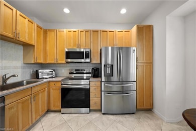 Kitchen with backsplash, light brown cabinets, sin