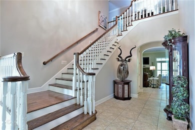 Stairs featuring arched walkways, a towering ceiling, tile patterned flooring, and ornamental molding