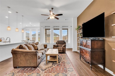 Living area with baseboards, ceiling fan, wood fi