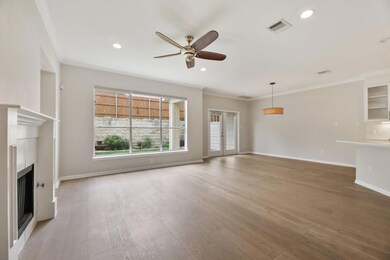 Unfurnished living room with crown molding, a fireplace, light wood-style flooring, french doors, and ceiling fan