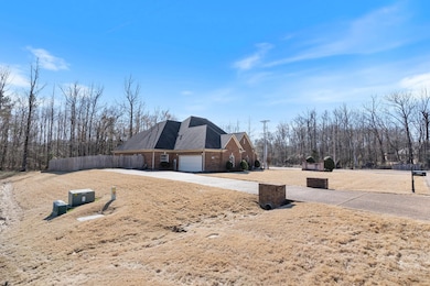 View of property exterior featuring a garage, driveway, brick siding, and fence