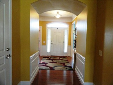 Grand entry foyer with wainscoting trim, hardwood floors, high baseboards.