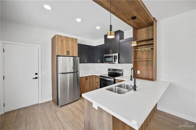 Kitchen featuring open shelves, a sink, light wood-style floors, a peninsula, and appliances with stainless steel finishes