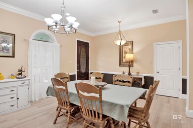 Dining space with light hardwood / wood-style floors, crown molding, and an inviting chandelier