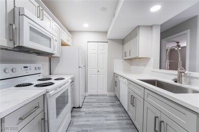 Kitchen featuring light wood-type flooring, sink, white appliances, and decorative backsplash