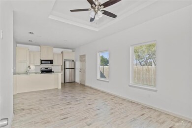 Kitchen featuring cream cabinets, open floor plan, stainless steel appliances, light countertops, and light wood-style floors