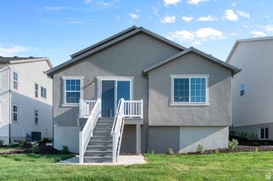 Back of property with central AC unit, a yard, and stucco siding
