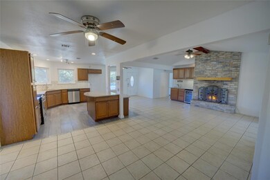 Kitchen featuring tasteful backsplash, open floor plan, light tile patterned floors, and a brick fireplace