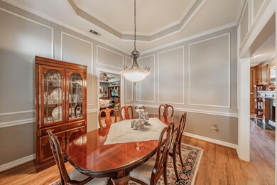 Dining area with ceiling fan, a raised ceiling, light wood-type flooring, and ornamental molding