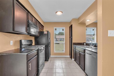 Kitchen featuring black appliances, a sink, dark 