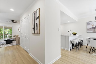 Corridor with ornamental molding, recessed lighting, and light wood finished floors