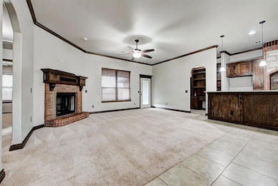 Unfurnished living room featuring arched walkways, light carpet, ornamental molding, a brick fireplace, and light tile patterned floors