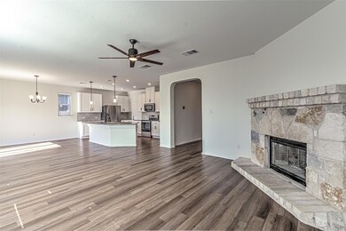 Unfurnished living room with arched walkways, a fireplace, dark wood finished floors, ceiling fan, and recessed lighting