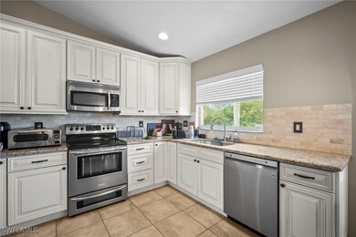 Kitchen featuring appliances with stainless steel finishes, light stone counters, light tile patterned floors, white cabinets, and recessed lighting