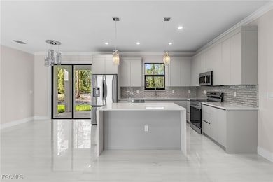 Kitchen with ornamental molding, modern cabinets, backsplash, a kitchen island, and stainless steel appliances