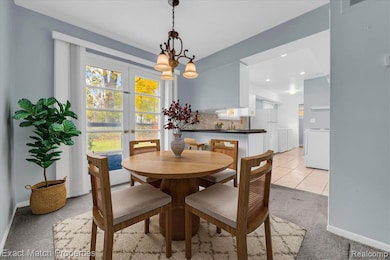Dining room featuring light carpet, light tile patterned flooring, a chandelier, washer / clothes dryer, and french doors
