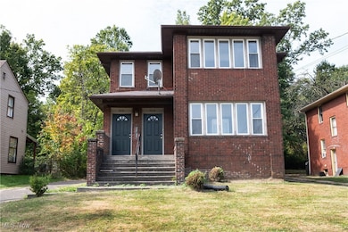 View of front of home with brick siding, a front yard, and covered porch