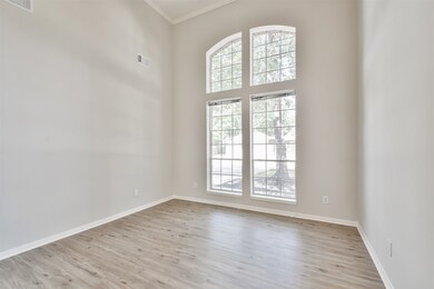 This room can be a study, Music room, 2nd living space down. Features high ceilings, updated flooring and paint, crown molding and a beautiful tree lined view.