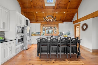 Kitchen with appliances with stainless steel finishes, wooden ceiling, a warming drawer, light wood-style flooring, and a chandelier