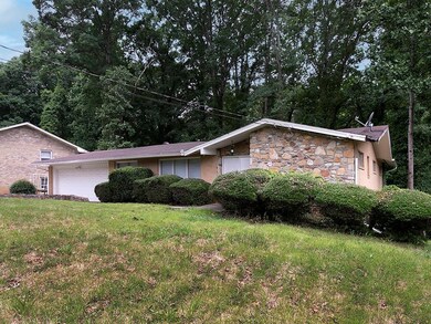 View of front of home with an attached garage, stone siding, and a front lawn
