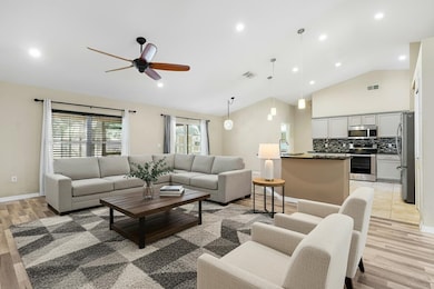 Living area with light wood finished floors, recessed lighting, ceiling fan, and high vaulted ceiling