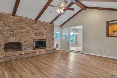 Unfurnished living room featuring beamed ceiling, baseboards, a fireplace, high vaulted ceiling, and ceiling fan with notable chandelier