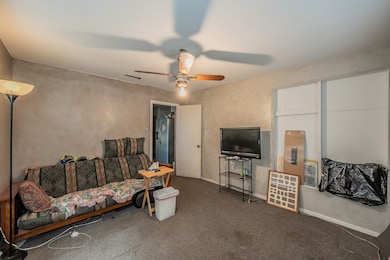 Carpeted living room featuring baseboards and ceiling fan