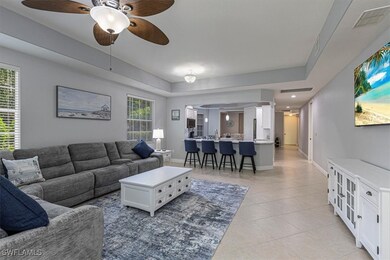 Living room with light tile patterned floors, a ceiling fan, and a raised ceiling