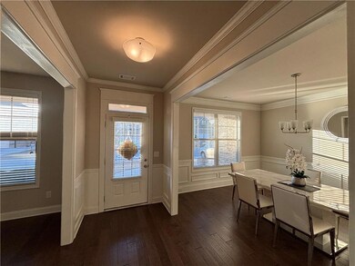 Entryway with an inviting chandelier, wainscoting, dark wood-style flooring, and a wealth of natural light