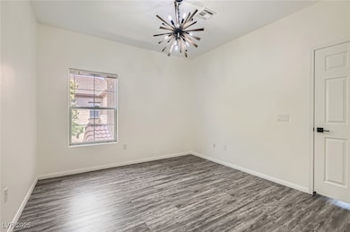 Spare room featuring a chandelier, dark wood-type