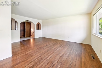 Unfurnished room featuring wood finished floors and arched walkways