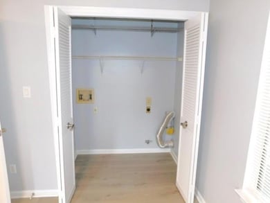 Laundry room with electric dryer hookup, washer hookup, and light wood-type flooring