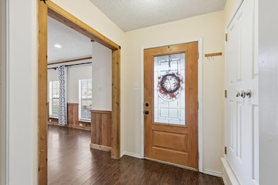 Entryway featuring a textured ceiling, dark wood-style floors, wainscoting, healthy amount of natural light, and wood walls