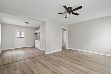 Unfurnished living room featuring light wood-style floors, a ceiling fan, and a textured ceiling