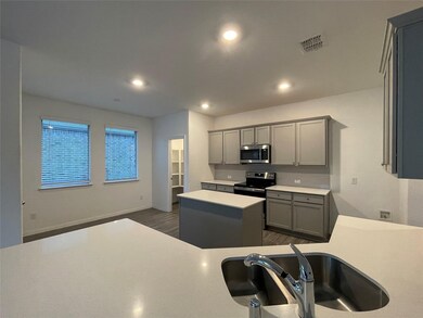Kitchen featuring gray cabinetry, a kitchen island, a sink, and stainless steel appliances