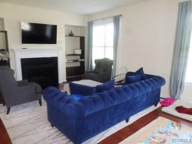 Living room with built in shelves, wood finished floors, and a fireplace