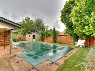 View of swimming pool featuring a diving board, a fenced backyard, a shed, and a patio area