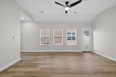 Spare room with light wood-style flooring, ceiling fan, and vaulted ceiling