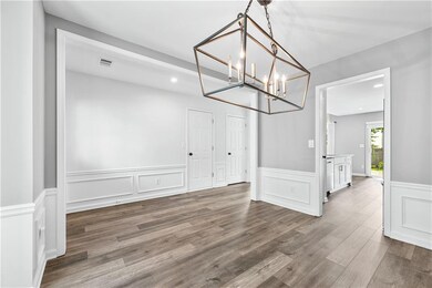 Unfurnished dining area featuring a decorative wall, wood finished floors, a chandelier, a wainscoted wall, and recessed lighting