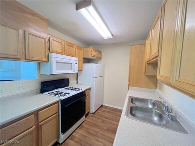 Kitchen with white appliances, light wood-style fl