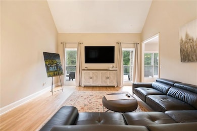 Living room featuring light wood finished floors, high vaulted ceiling, and baseboards