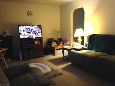 The living room  has neutral carpeting and paint.