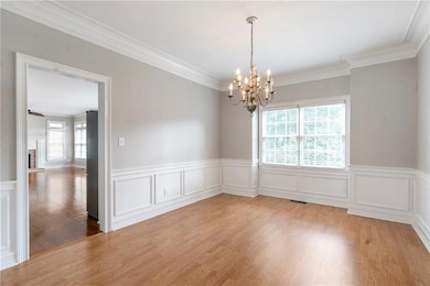 Spare room featuring healthy amount of natural light, crown molding, a chandelier, wood finished floors, and a brick fireplace