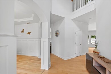 Hall with light wood-style flooring, arched walkways, wainscoting, and a decorative wall