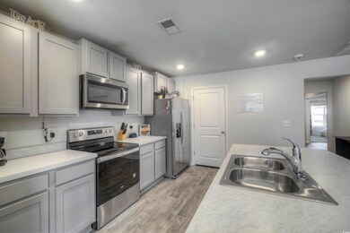 Kitchen with visible vents, light wood-style flooring, a sink, light countertops, and appliances with stainless steel finishes